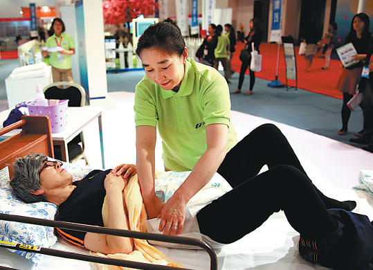 A nursing worker attending the fourth China International Senior Services Expo in Beijing on May 6 shows how she cares for the elderly. Photo Pan Xu/Xinhua