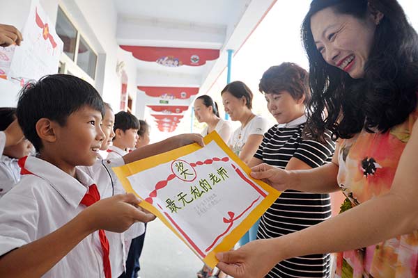 Students give their teachers handmade certificates of merits to express their gratitude on Thursday, Teachers' Day, at a primary school in Handan, Hebei province. HAO QUNYING /CHINA DAILY