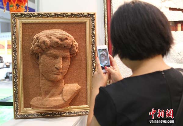 A woman takes a photo of a portrait of David at an art exhibition in Chongqing. (Photo/Chinanews.com)