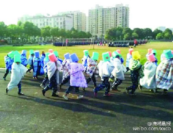 Students wrapped in quilts had to run across a field wearing plastic buckets on their heads. (Photo/Weibo.com)