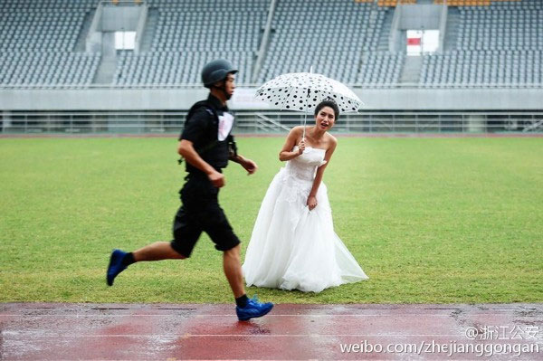 Dressed in her wedding gown and holding an umbrella against the rain, the bride cheers her husband-to-be in the rain. (Photo/Weibo.com)