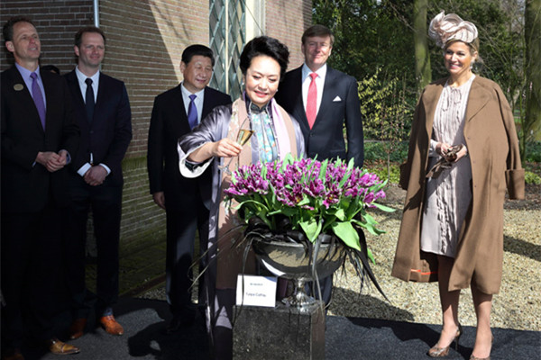 Peng Liyuan (C), wife of China's President Xi Jinping (L), baptizes the tulip Cathay on the second day of their state visit to the Netherlands March 23, 2014. (Photo/Xinhua)