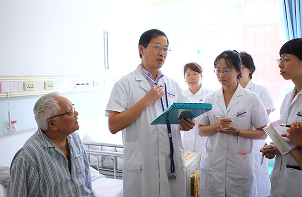 Yu Zhenqiu, director of the hypertension department at Anzhen Hospital in Beijing, visits a patient on a ward. Provided to China Daily