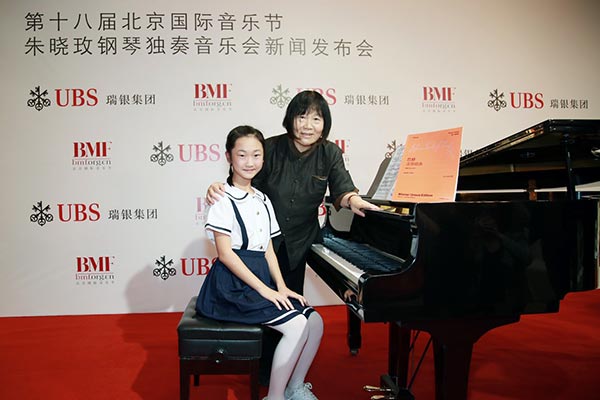 Zhu Xiaomei takes a photo with the girl who performed at the press conference for the concert held at the St Joseph's Church in Beijing on Monday. The concert, sponsored by UBS, is part of the Beijing Music Festival. (Photo provided to chinadaily.com.cn)