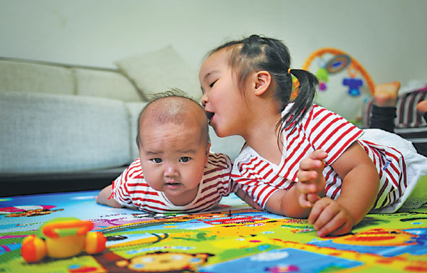 A girl and her brother play together at their home in Fuzhou, Fujian province. The little boy was born after changes to China's family planning policy last year that allowed couples to have two children if one partner is an only child. Provided to China Daily