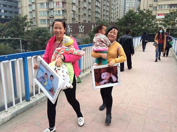 Two mothers hold their babies after getting their photos from a studio on Wednesday in Xi'an, Shaanxi province. The mothers said they are considering having a second child. Hu Guoqing / for China Daily