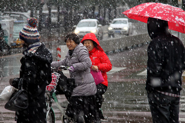 Local residents go out in the snow in Beijings Xicheng district on Friday. Snow fell unexpectedly early in Beijing and other cities in northern China on Friday, causing traffic problems for millions of people and prompting the capital to provide heating for residential complexes ahead of schedule. (Photo: China Daily/Yan Xiaoqing)