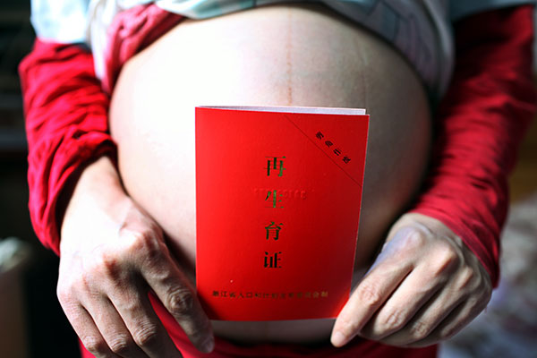 A birth approval certificate for a second child is shown by a pregnant woman in Quzhou, Zhejiang province, in April last year.(XU YUANCHANG/CHINA DAILY)