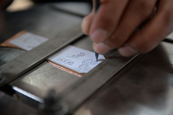 One of Jin's apprentices engraves decorations on the black copper, Nov 19, 2015. (Photo by Tan Qing/For chinadaily.com.cn)