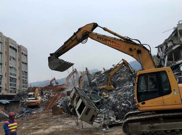 A rescue vehicle works on a debris of a factory building after a landslide occurred in Shenzhen. Strong signals of life have been detected on Monday. (Photo by Chai Hua/chinadaily.com.cn)