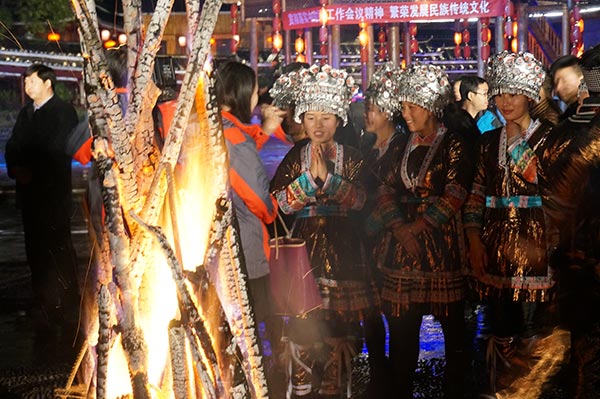 A Dong woman prays in front of a bonfire lit near their gulou, Jan 13, 2016. (Photo by Yang Jie/chinadaily.com.cn)