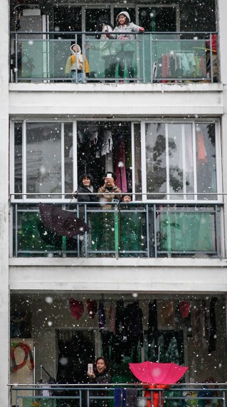 Residents enjoy the snow from their balconies in Panyu, Guangdong province, on Sunday. (Photo: China Daily/Chen Zhigang)