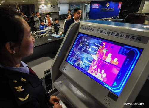 A staff worker of inspection and quarantine administration looks at the screen of body temperature monitoring equipment at Guangzhou Baiyun International Airport in Guangzhou, south China's Guangdong Province, Feb. 16, 2016. (Photo: Xinhua/Liu Dawei)