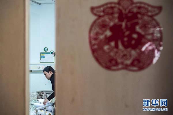 Wu Jun's wife Chen Si takes care of Wu Jun in the hospital on Feb 19. (Photo/Xinhua)