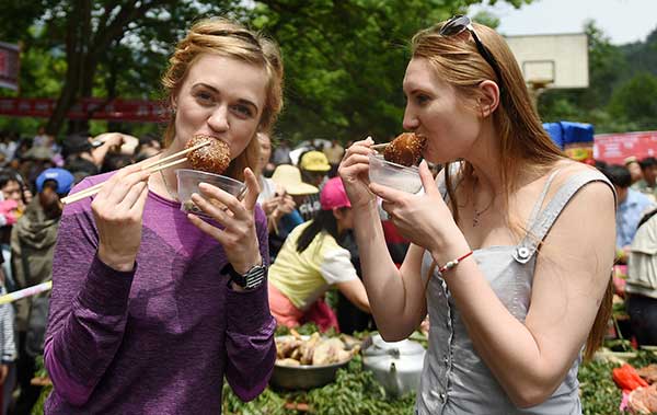 Two visitors from Russia taste local snacks in Rongshui, Guangxi Zhuang autonomous region.(Photo/Xinhua)