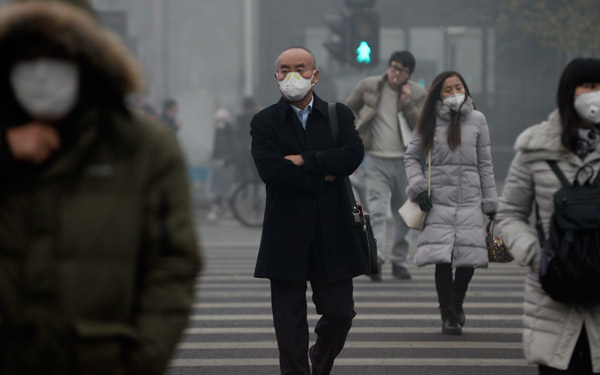 Pedestrians cross the road in Zhongguancun, Beijing, during a smoggy day in December.(Photo/China Daily)