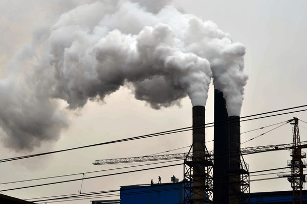 Smoke is emitted from chimneys at Gengchen Casting Materials Corp in Jinan, Shandong province, as lingering smog shrouds the city. (Photo/Xinhua)