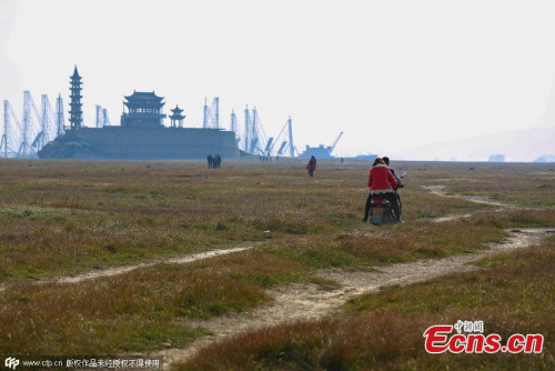 An island stands in Poyang Lake after water level declines in Xingzi county, Jiujiang city, East Chinas Jiangxi province, Jan 3, 2015. Due to persistent drought and less runoff from the upstream, the countys landmark is now accessible by walking, rather than a boat during the wet season. (Photo/CFP)