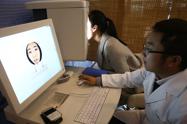 A doctor looks at a patient's face and tongue to make a diagnosis on screen at Wuzhen Internet Hospital's offline hospital. (Photo by Zou Hong/China Daily)