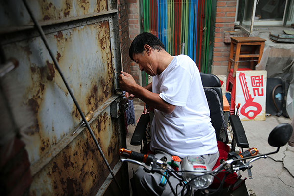 Yang Yufang fixes a lock at his home. WANG ZHUANGFEI/CHINA DAILY