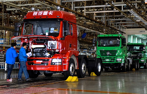 Workers check heavy-duty trucks in a factory of Shaanxi Automobile Holding Group Co Ltd in Xi'an, Shaanxi province. (Photo provided to China Daily)