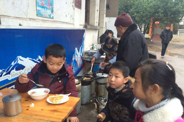 Students of Huangtankou Primary School eat breakfast at Huang Shihua's food stall. (Photo/Zhejiang News)