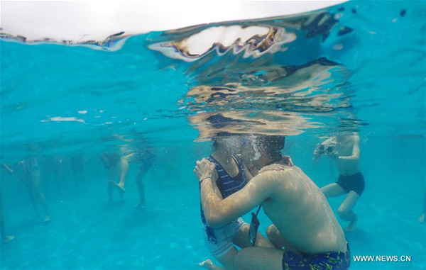 A couple participates during an underwater kiss contest held at a water park in Shanghai to welcome the Qixi Festival, July 17, 2016.  (Photo/Xinhua)