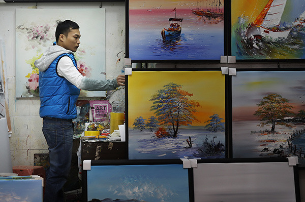 A worker arranges oil paintings at an art gallery in Dafen. (Photo by Xu Yuanchang/China Daily)