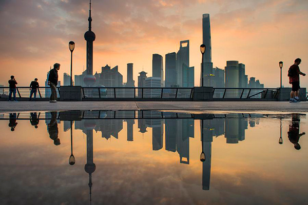 Skyscrapers and people reflected in a puddle of water in the early hours of the morning at the Bund in Shanghai, Oct 20, 2015. (Photo/Xinhua)