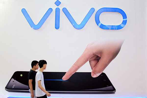 Two pedestrians walk past a Vivo Mobile Communication Technology Co Ltd poster in Nanjing, Jiangsu province.(Photo/China Daily)