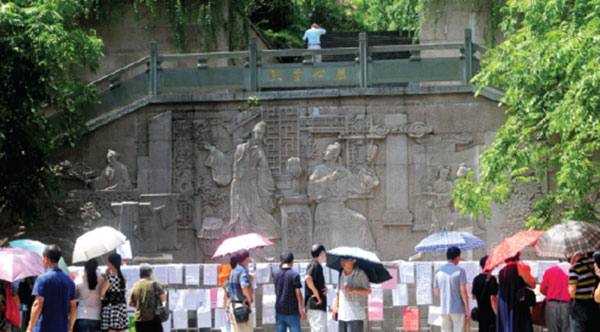 Parents read posters strung up on a line between two light poles next to the main entrance of the Wansong Shuyuan in Hangzhou. (Photo by Xing Yi/China Daily)