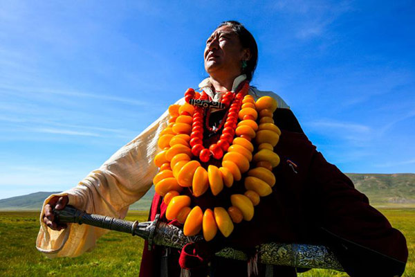 Kangba men's costume is more simple and loose, compared with the women's, and show off their masculinity and strength. Men's accessories made of amber and corallites are larger and also heavier. (Photo by Han Jiajun/chinadaily.com.cn)