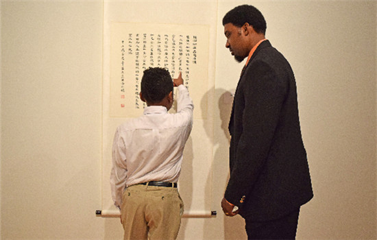 Menelik Gurnell, a student from Global Learning Village, reads a poem aloud to his father. (TIFFANY WANG / FOR CHINA DAILY)