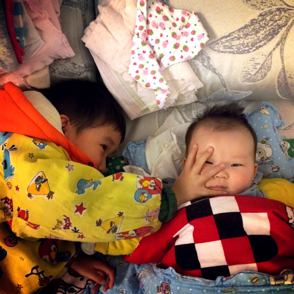 A boy reaches out to touch the face of his younger sister in Wuhan, Hubei province. (Photo by Kun Shao / For China Daily)