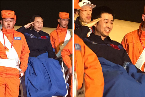 Chinese astronauts Jing Haipeng (L) and Chen Dong salute as they are carried off the plane that brought them to Beijing on Friday evening. The two had returned to Earth earlier the same day after a monthlong space mission.(Photo: Xinhua/Yang Xin)