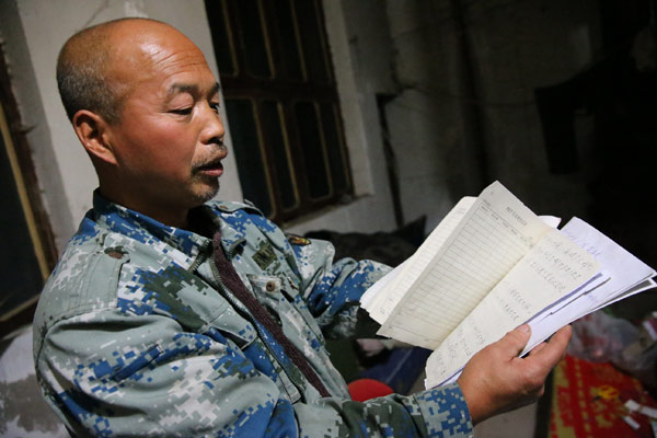 Migrant worker Li Jian with the manuscript of his third book at the room he has rented in Xi'an, Shaanxi province. (Photo by Deng Xiaowei/China Daily)