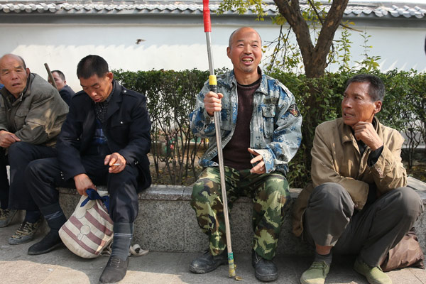 Li Jian (second from right) and his fellow workers have a break at a construction site in Xi'an. (Photo by Deng Xiaowei/China Daily)