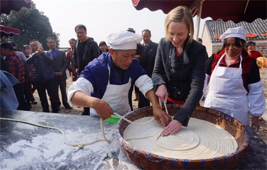 Rose tries hopelessly to wind rice noodles in a spiral before they are stretched out and hung out to dry. (Photo by Chen Ziyan/chinadaily.com.cn)