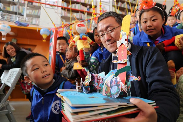 Yan Hongbing, the paper-art designer of the book, with children at a promotional event in Xi'an. (Photo provided to China Daily)