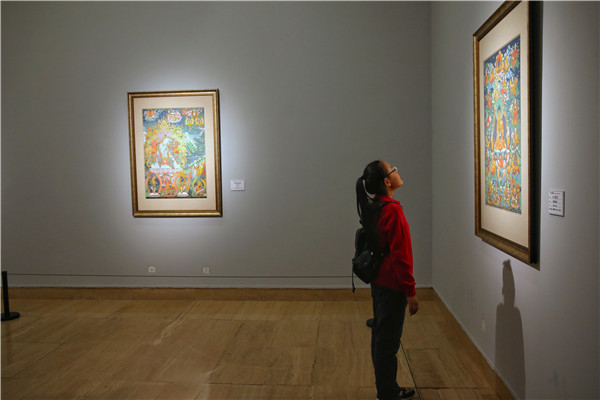 A girl visits the ongoing thangka exhibition, Heavenly Tibet, at Beijing's National Art Museum of China. The dozens of paintings on show mostly feature Buddhist thangka produced in recent years. (Photo by Jiang Dong/China Daily)