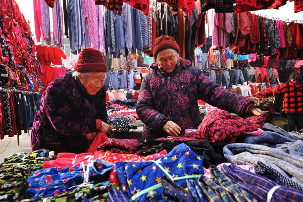 Farmers look at clothes at a market in Zaozhuang city's Shanting district, in East China's Shandong province, before the Spring Festival.Li Zongxian / For China Daily