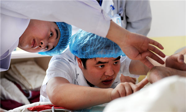 Wu Xufeng (right) treats a patient in the intensive care unit at the Hefei Binhu Hospital, Anhui province. (Photo/China Daily)