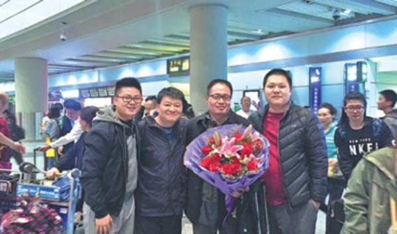 Colleagues of Cao Hongguo gather at the airport to welcome him back home.  (Photo/China Daily)