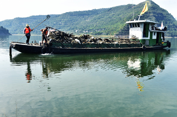 Workers remove floating objects from the Xiaojiang River, a tributary of the Yangtze River, in Chongqing in October. (Photo by Rao Guojun/For China Daily)