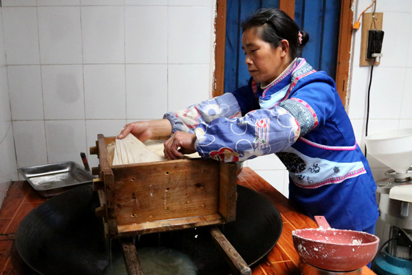 A woman from the Mulao ethic group makes traditional tofu using the group's age-old recipes. (Photo by Yang Jun/China Daily)