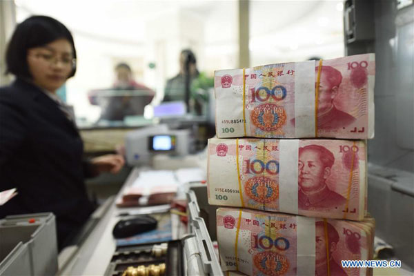 A bank staff member checks renminbi notes at a bank in Lianyungang, East China's Jiangsu province, Jan 7, 2016. (Photo/Xinhua)