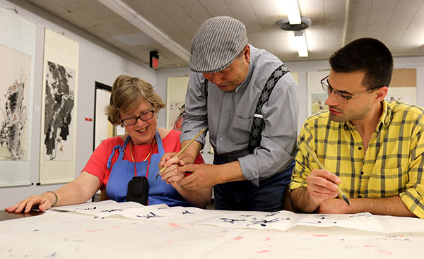 Liu Shuling, a Chinese artist (center), teaches Western Kentucky University faculty Carol Watwood and Daniel Peach how to hold a brush after lecturing at the university's Confucius Institute in Bowling Green on Wednesday.(Zhao Huanxin/China Daily)