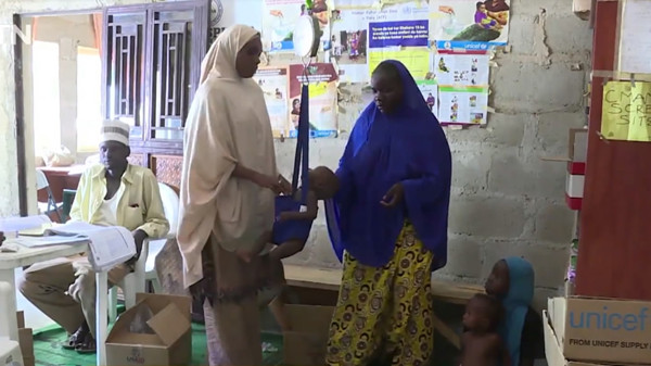 A staff member in a children's clinic in Dalori IDP camp weighs Bala Umar. (CGTN Photo)