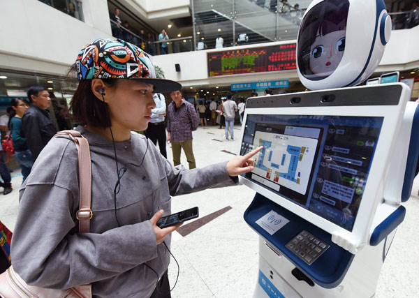 A Hangzhou resident operates a medical service robot at the outpatient lobby of a local hospital. LONG WEI / FOR CHINA DAILY