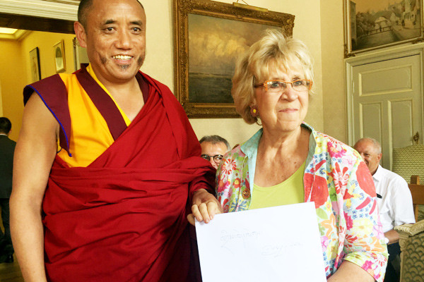 Luosongjiangcun, an executive with the Buddhist Association of the Tibet Autonomous Region of China, wrote best wishes in Tibetan for a participant in a seminar on Tibetan culture and history at the City Hall in Huy, Belgium, on Thursday. Fu Jing/China Daily